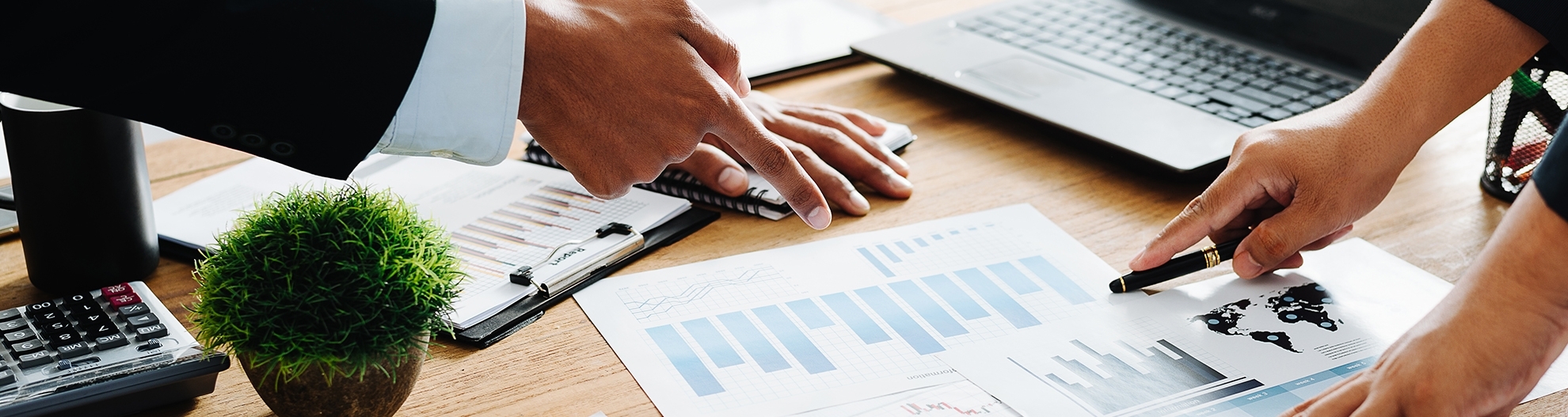 Closeup of professionals pointing at charts on desk